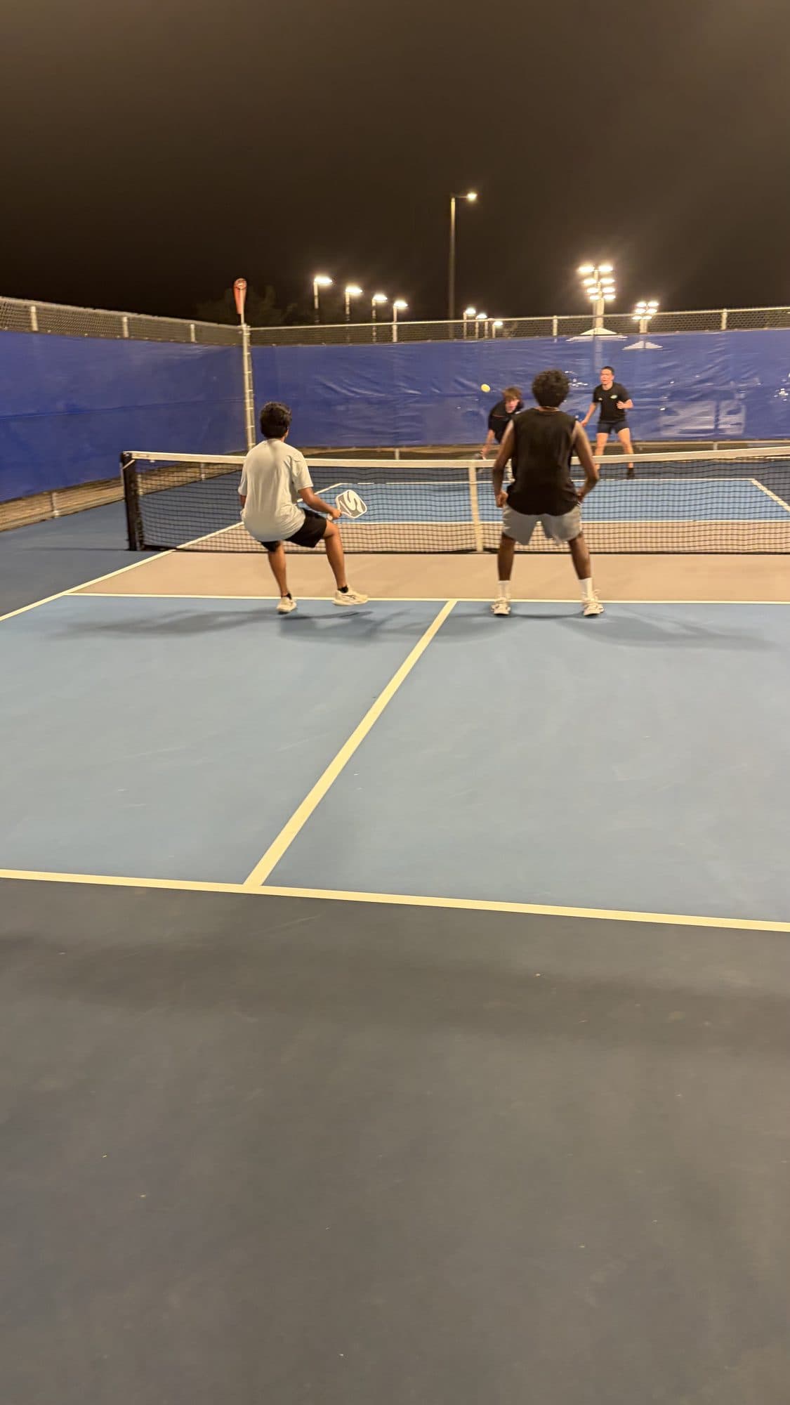 Four players in a doubles point with both teams pressed up to the net